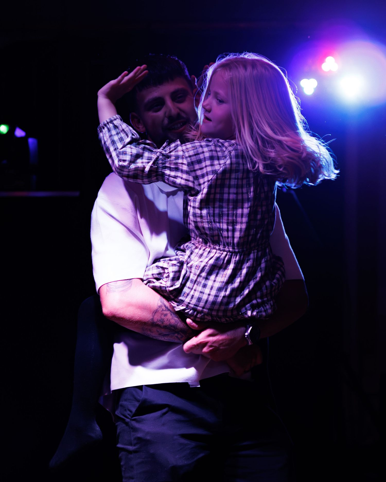A couple dances intimately under dramatic blue and purple stage lighting during a performance.