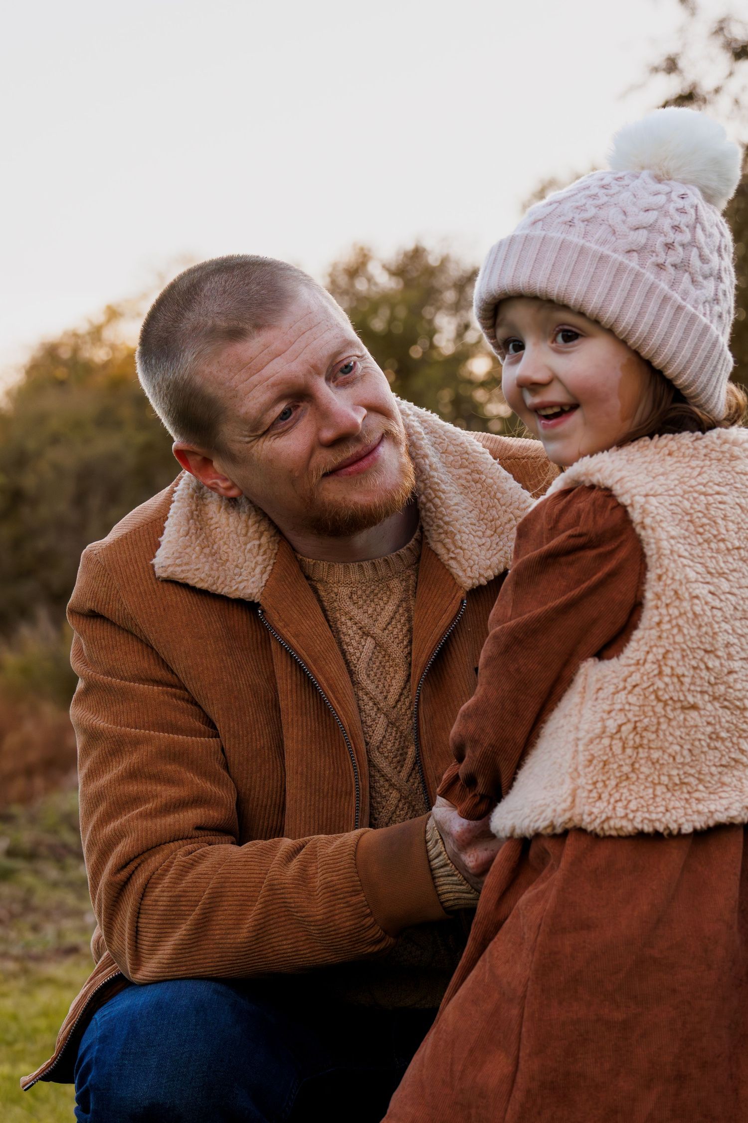 A heartwarming outdoor portrait of parent and child in warm winter coats sharing a tender moment at sunset.