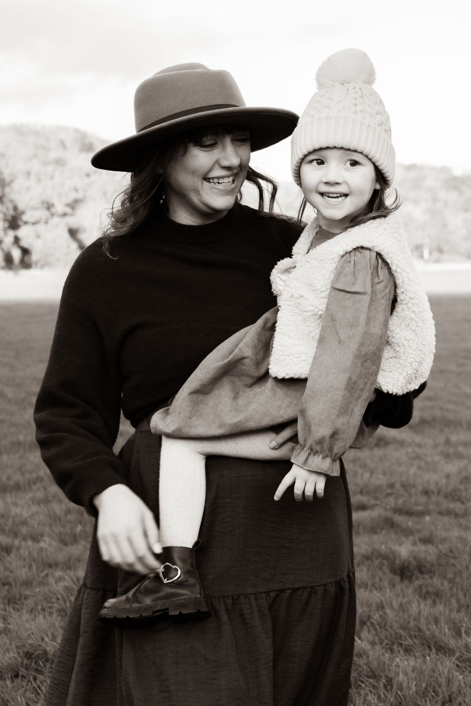 A black and white photo series showing a couple embracing outdoors in winter clothing and hats.