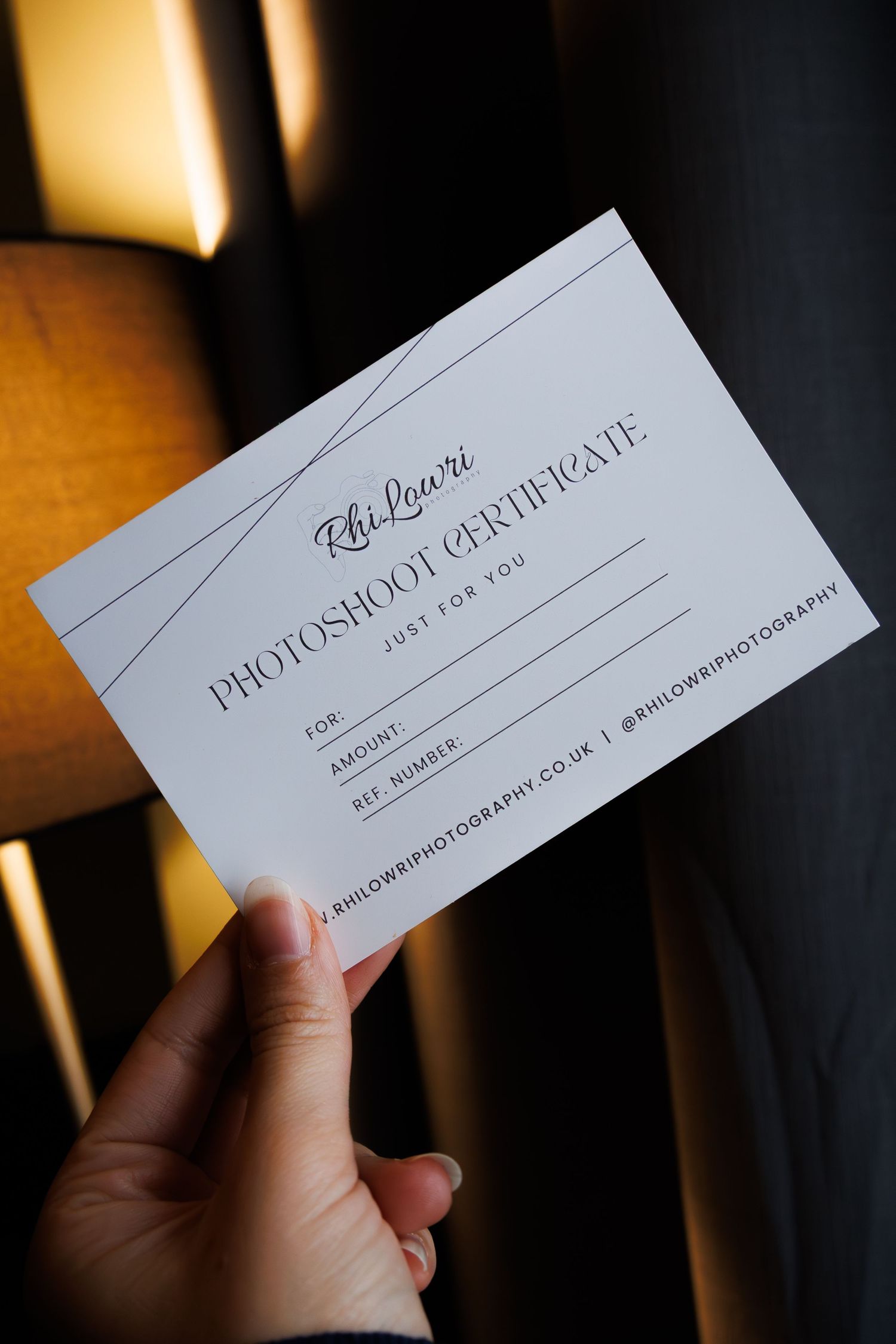Hand holding a white business card with Photoshika text against dark background in multiple angles.