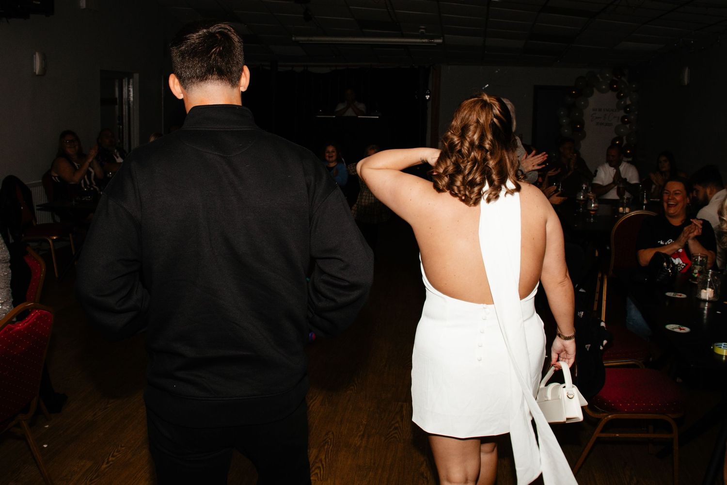 A group of people dancing and socializing at a dimly lit party or event venue.