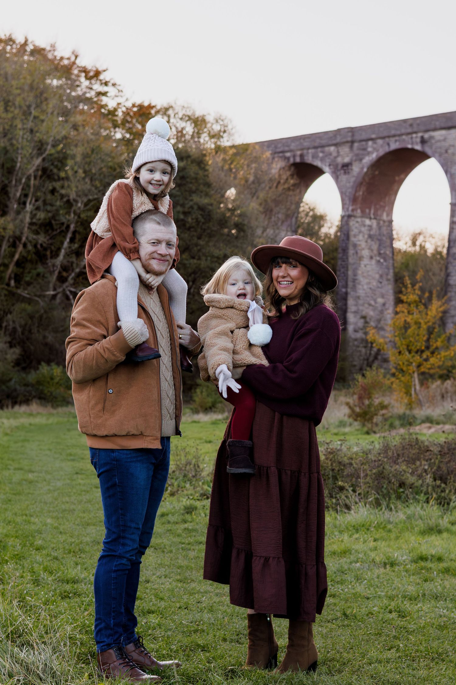 A couple stands together outdoors in autumn near a stone bridge, sharing tender moments in a series of connected photos.