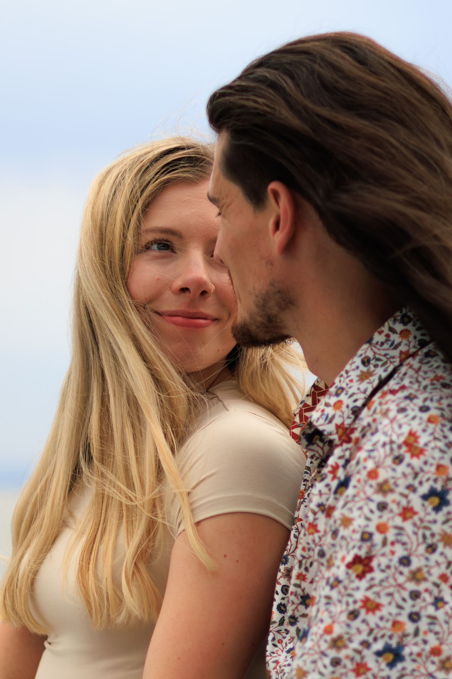 A couple in a romantic moment share tender glances while wearing casual summer attire.