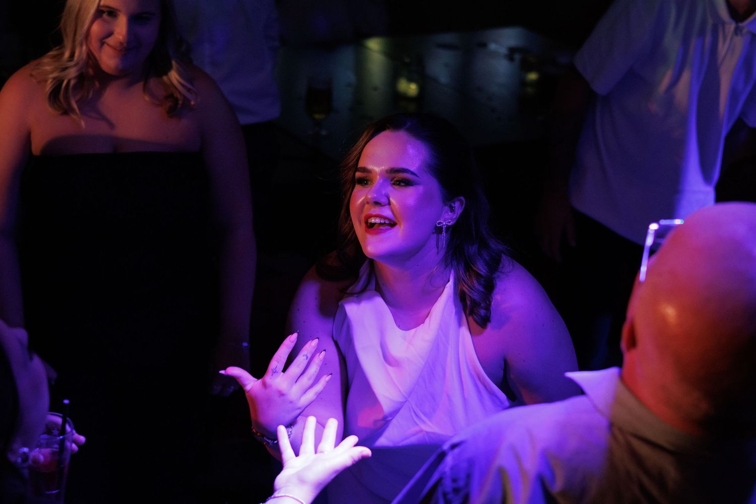 People dancing and celebrating at a nightclub with purple lighting and energetic atmosphere.