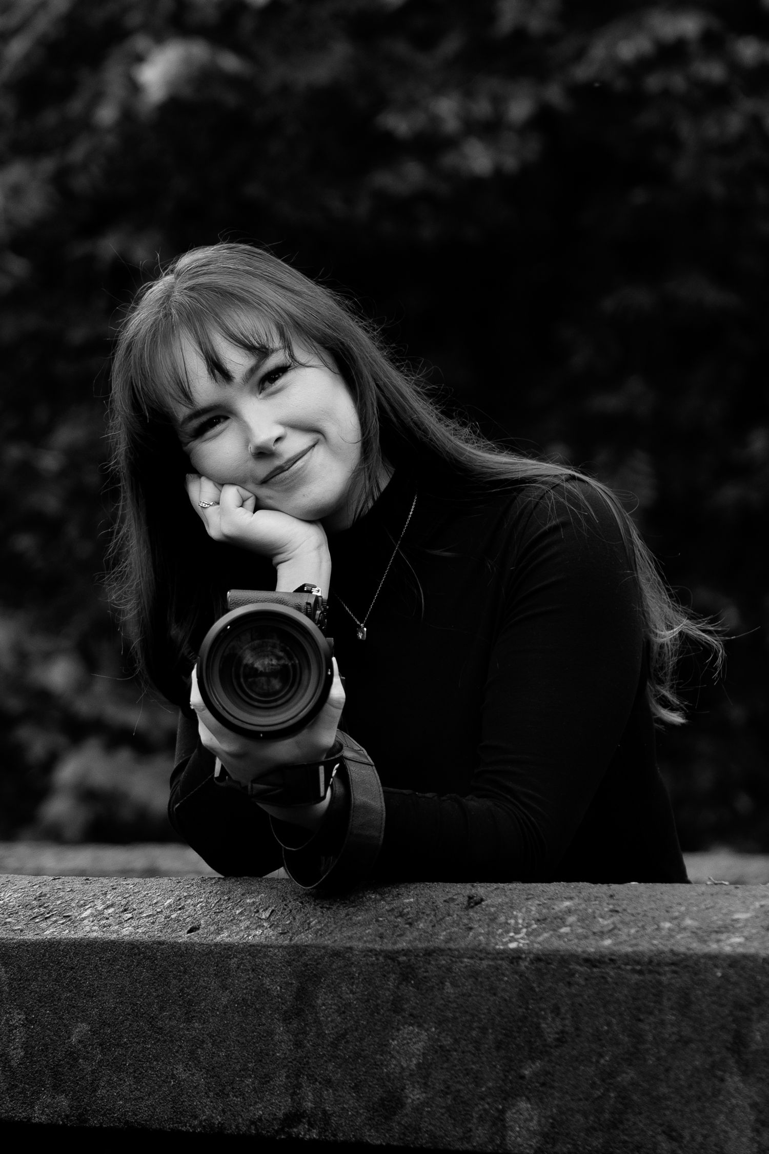 Black and white portrait series showing someone lying down with a camera in moody artistic poses against a dark background.