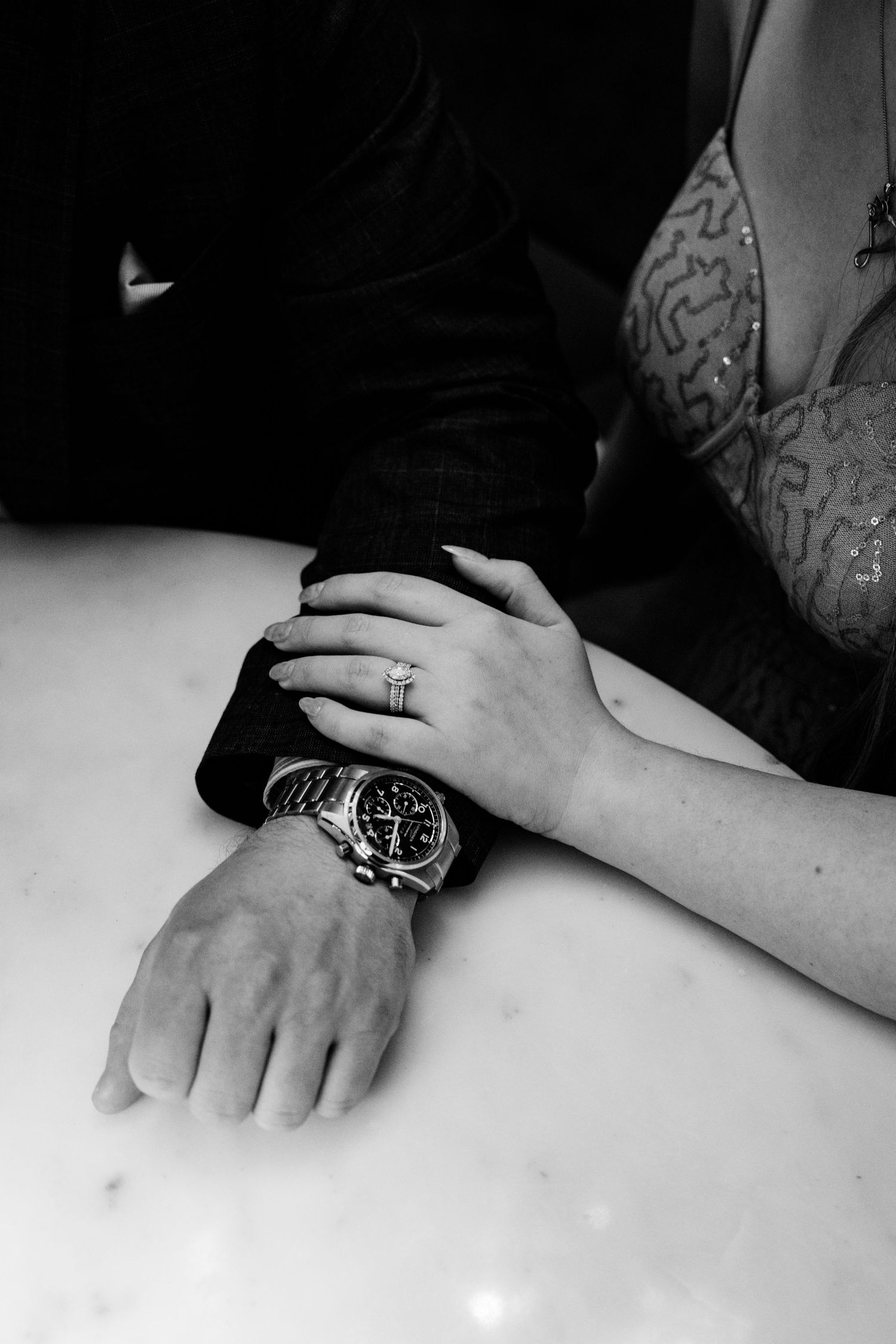 A black and white photo series showing close-up shots of hands wearing rings on a white surface.