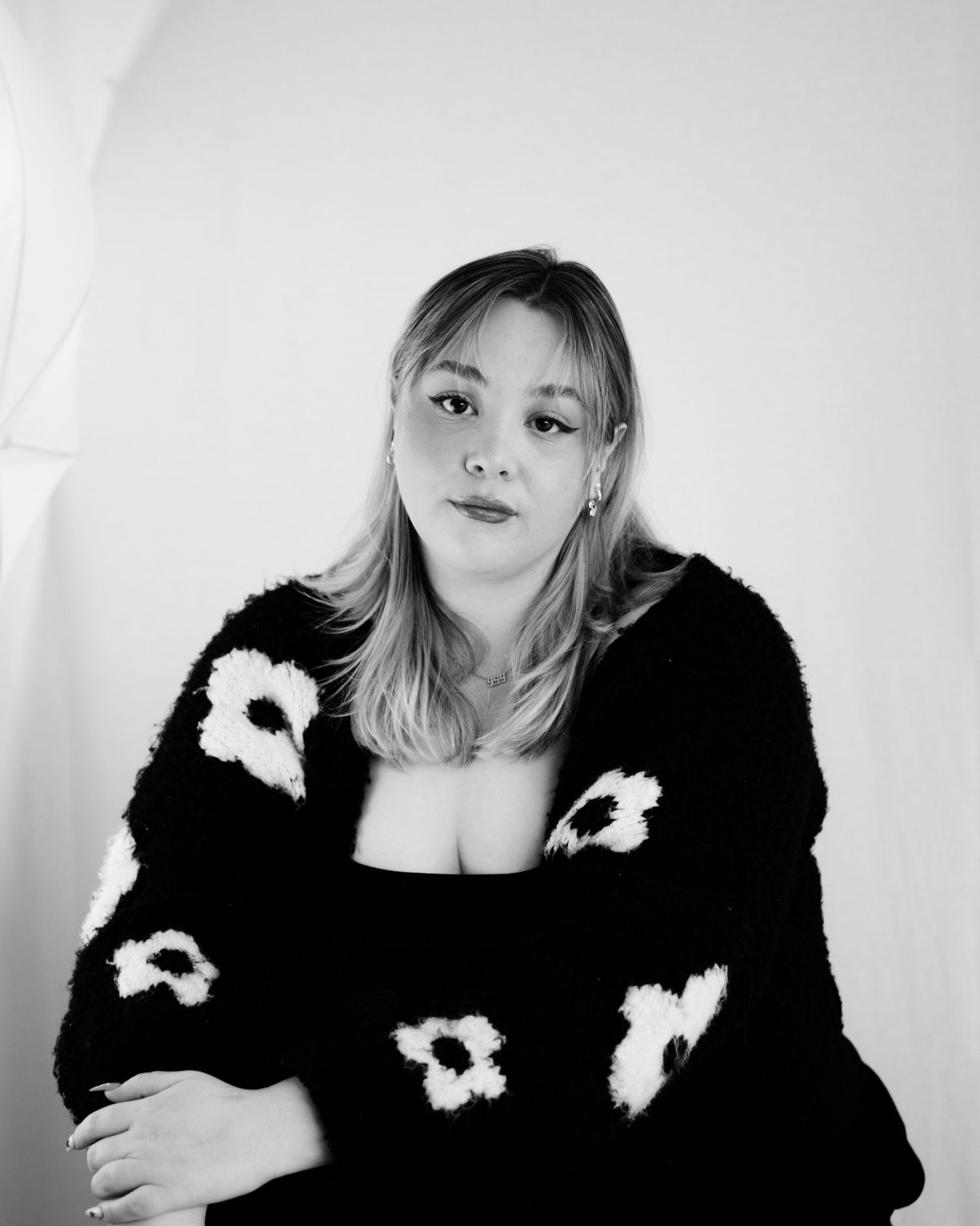 A series of black and white fashion portraits showing someone in a dark jacket with white floral accents.
