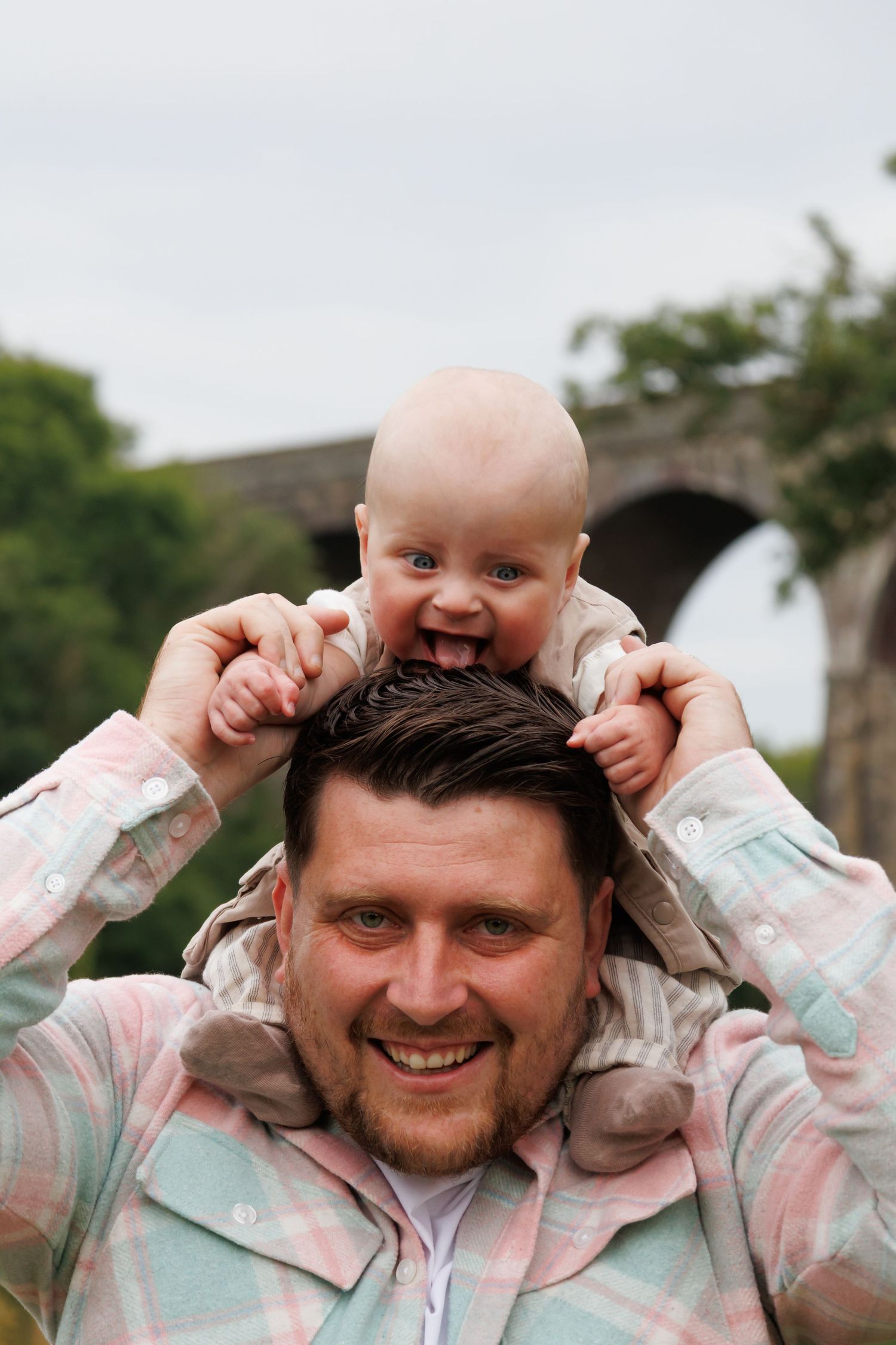 A series of photos showing playful interaction between a father and baby outdoors with joyful expressions and gestures.