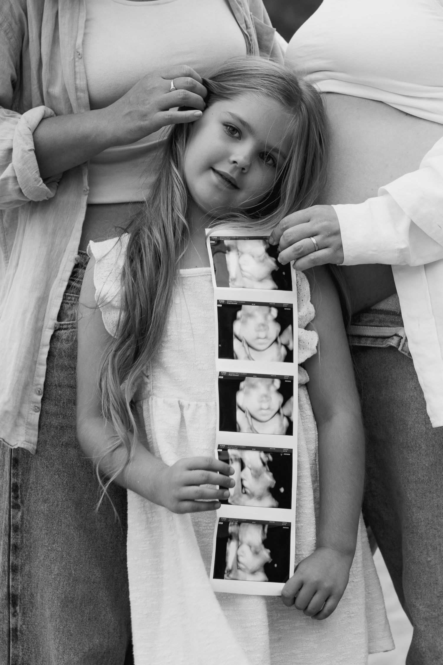 Black and white photo series showing a child admiring ultrasound photos while someone holds them.