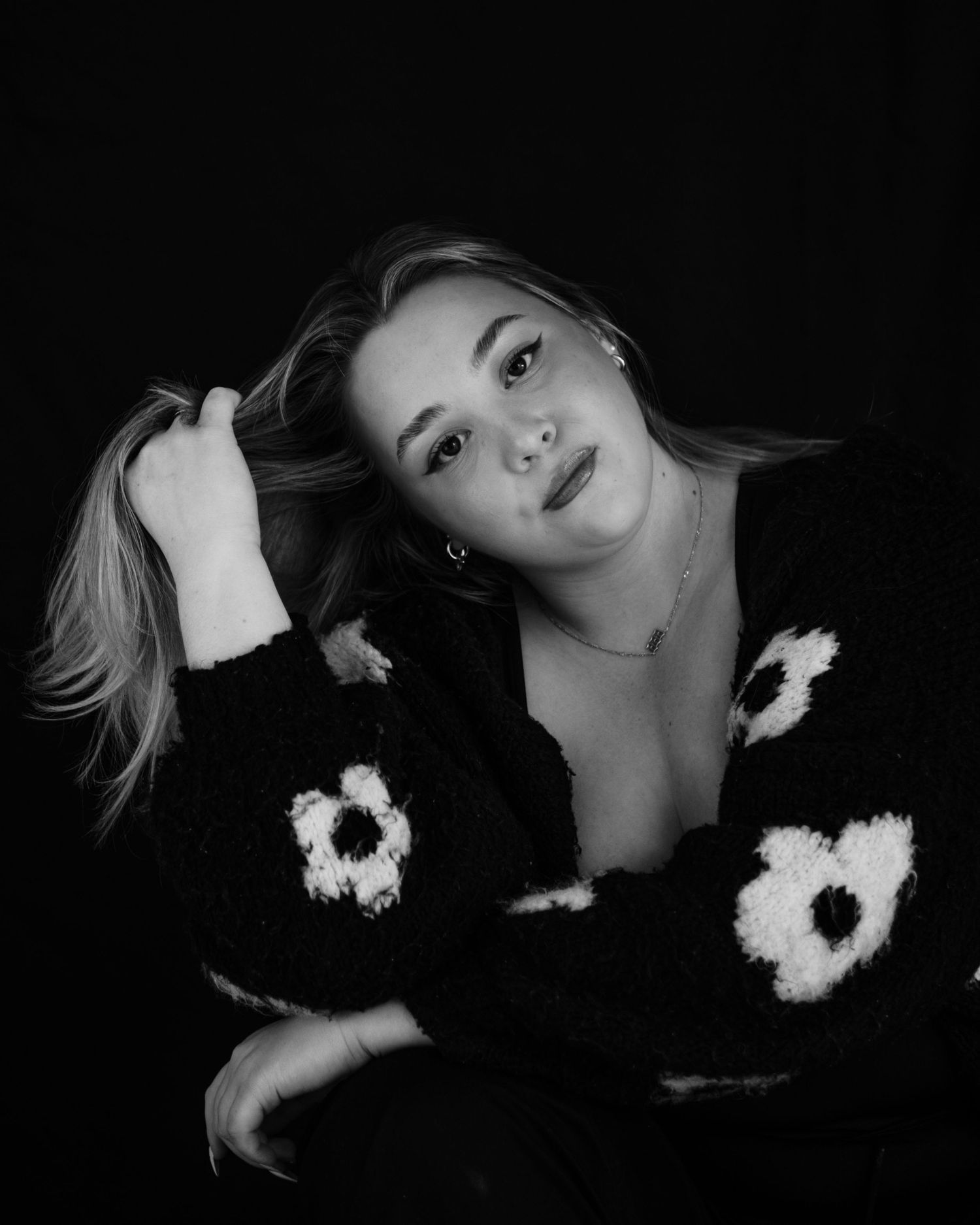 A dramatic black and white photo series showing a figure with white floral decorations against a dark background.
