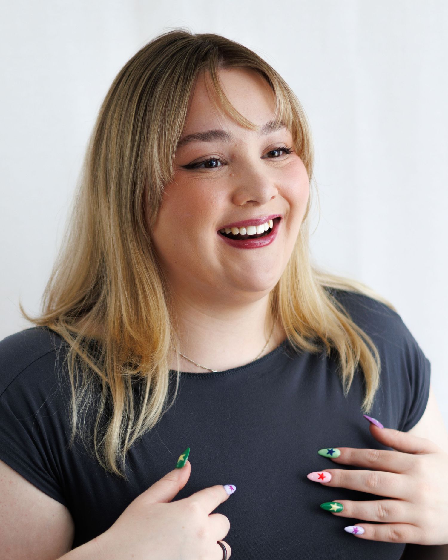 A series of photos showing a person in a black shirt laughing and gesturing with painted fingernails against a white background.