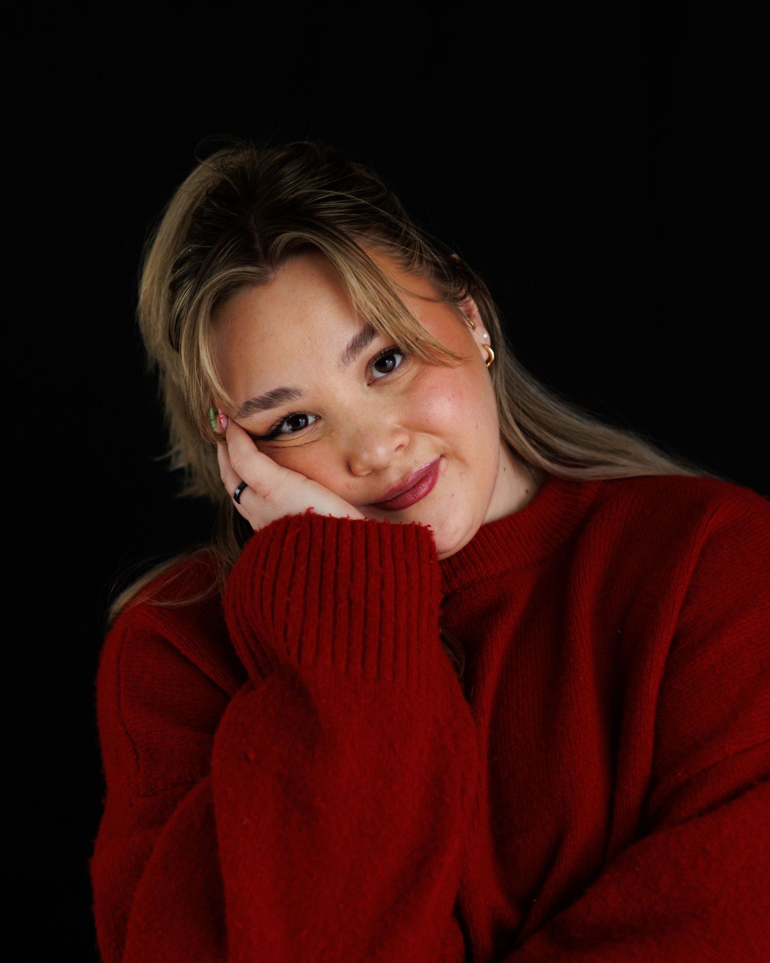 A person wearing a red sweater poses against a dark background in a series of moody portrait shots.