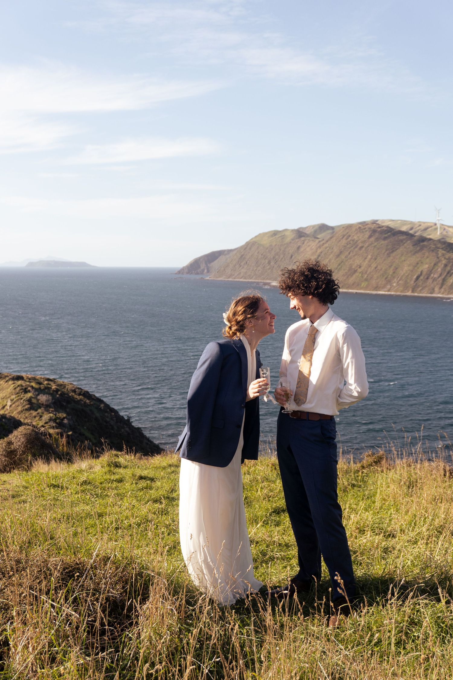 Couple shares intimate moments against coastal cliff backdrop with ocean views.