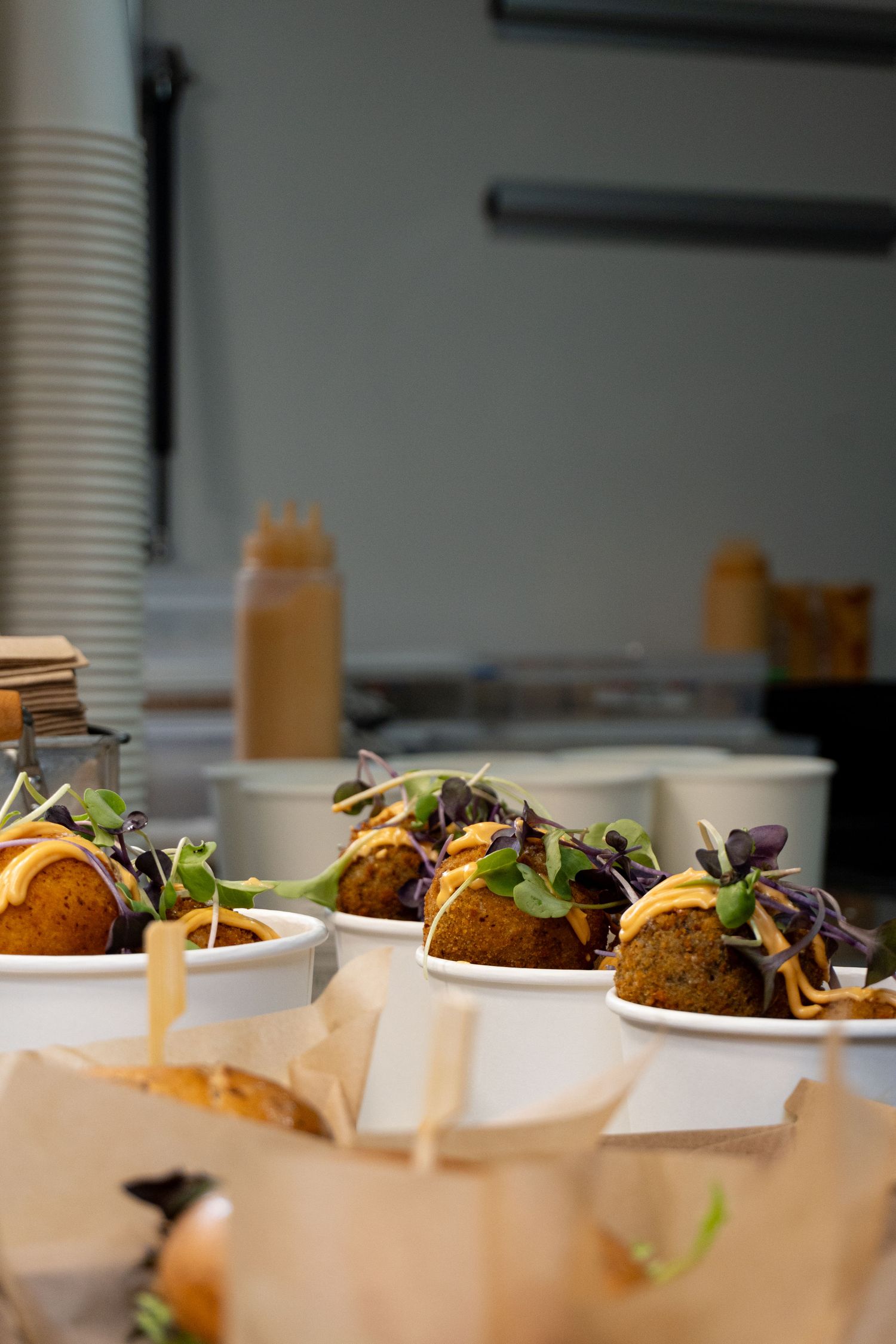 Gourmet tacos garnished with microgreens served in white bowls at a catered food event.