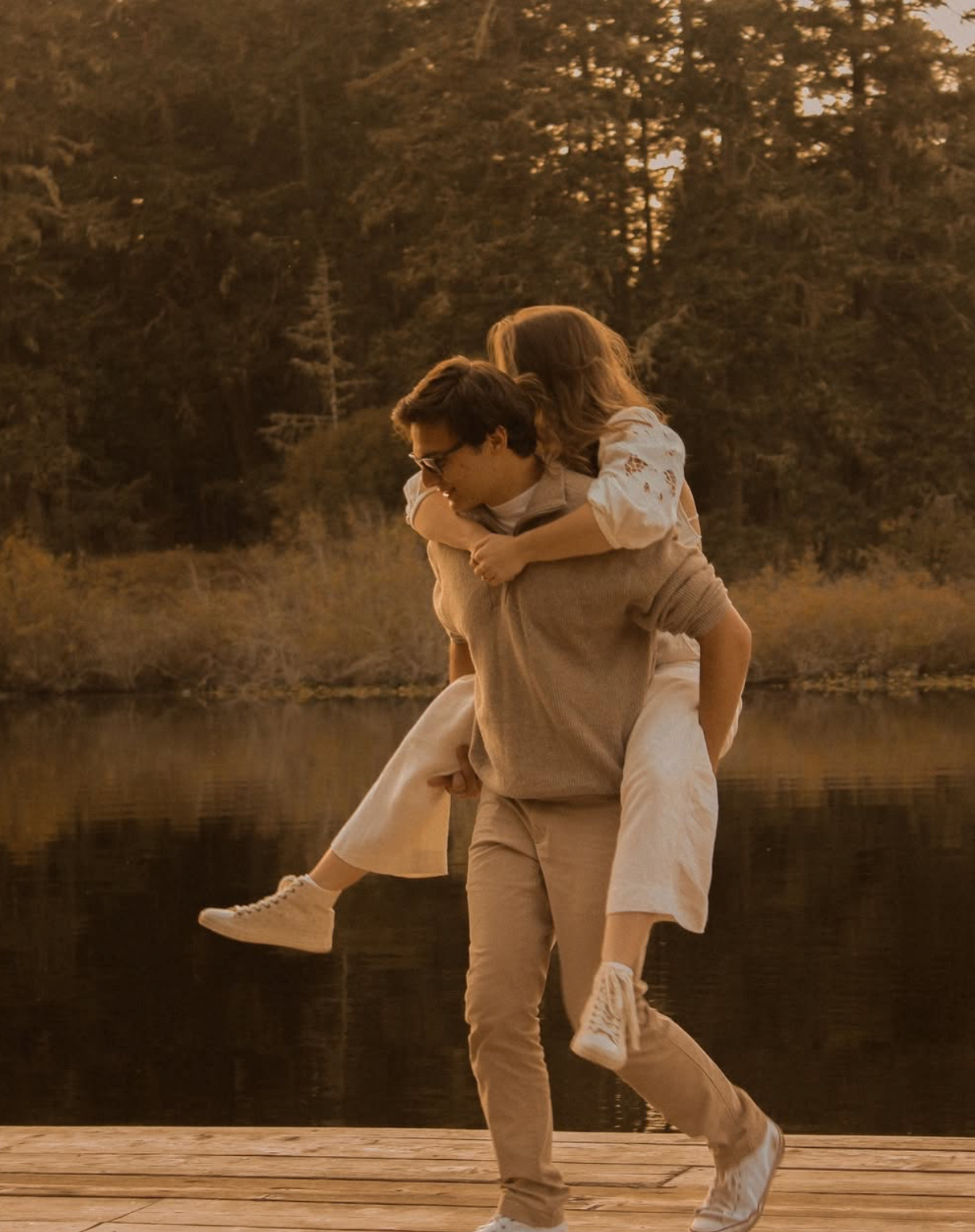 Sepia-toned sequence of couple dancing and spinning by a lake at sunset.