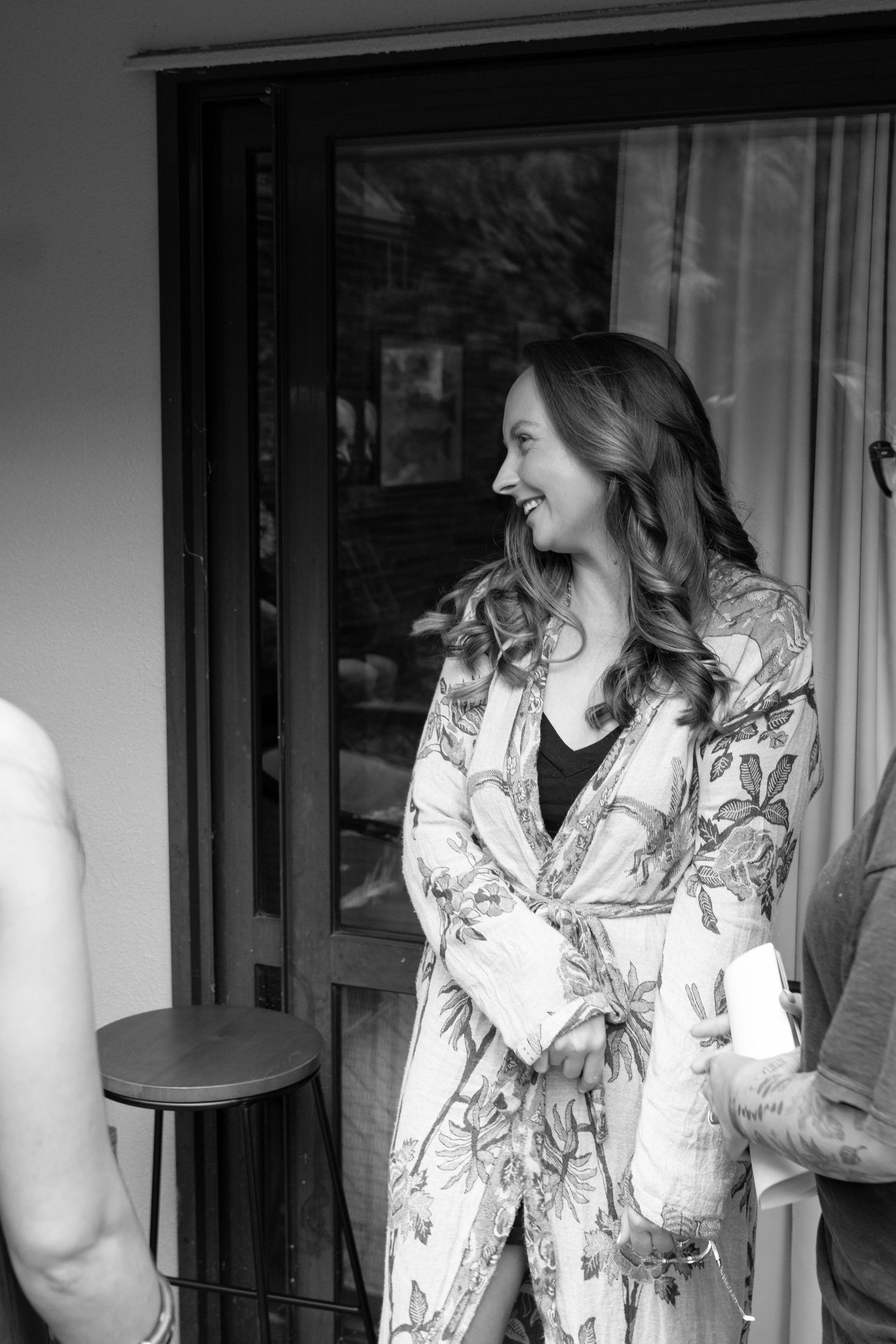 Woman in floral robe smiling and laughing in black and white candid photo.
