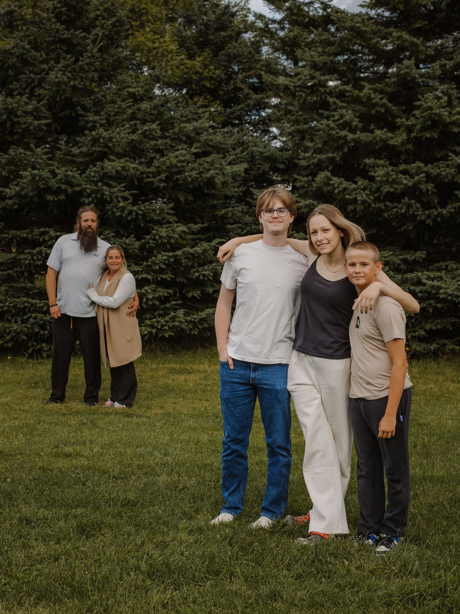 A mother and father watch their children hug in the foreground.