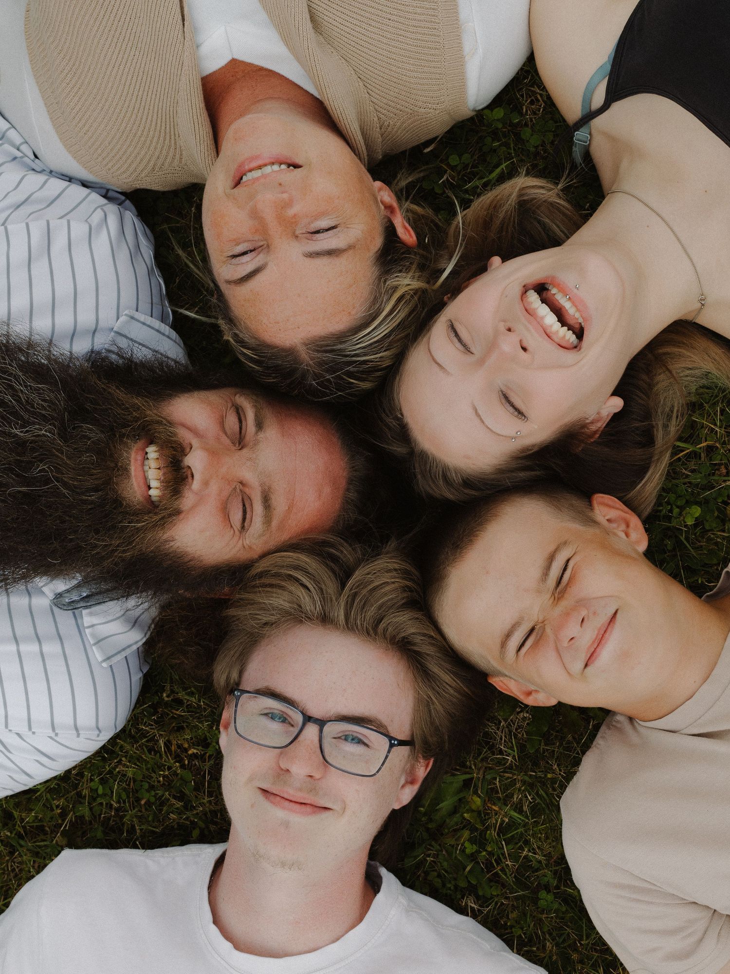 A family lays in a circle with their heads together, laughing.