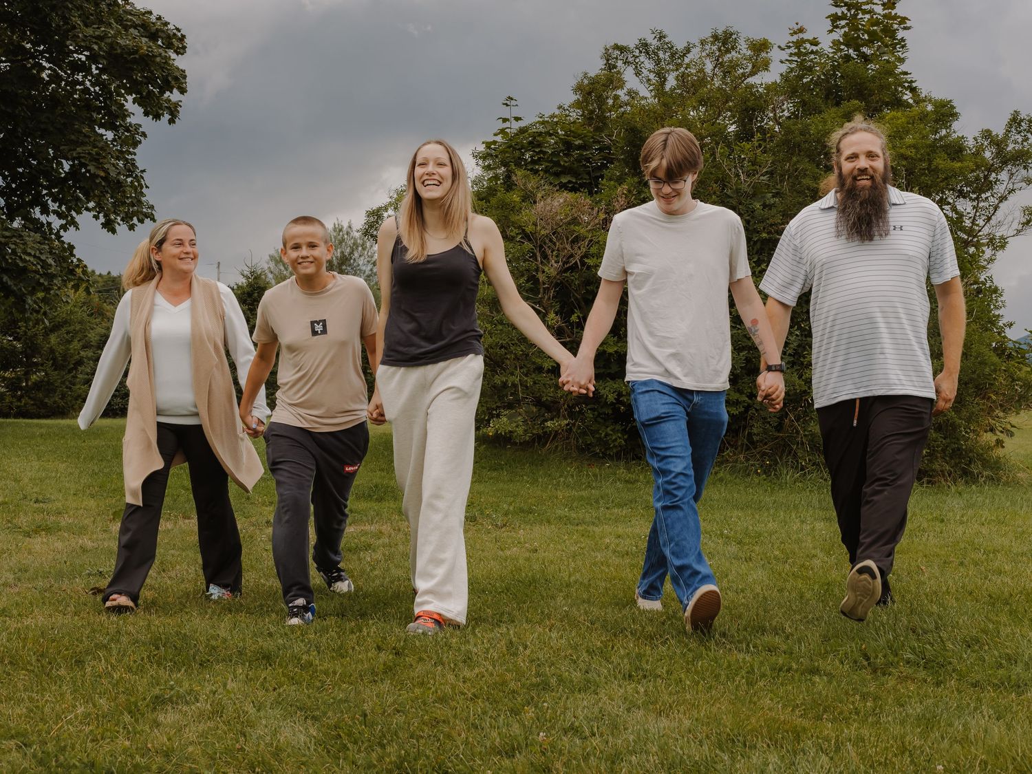 A family walks hand-in-hand through a field