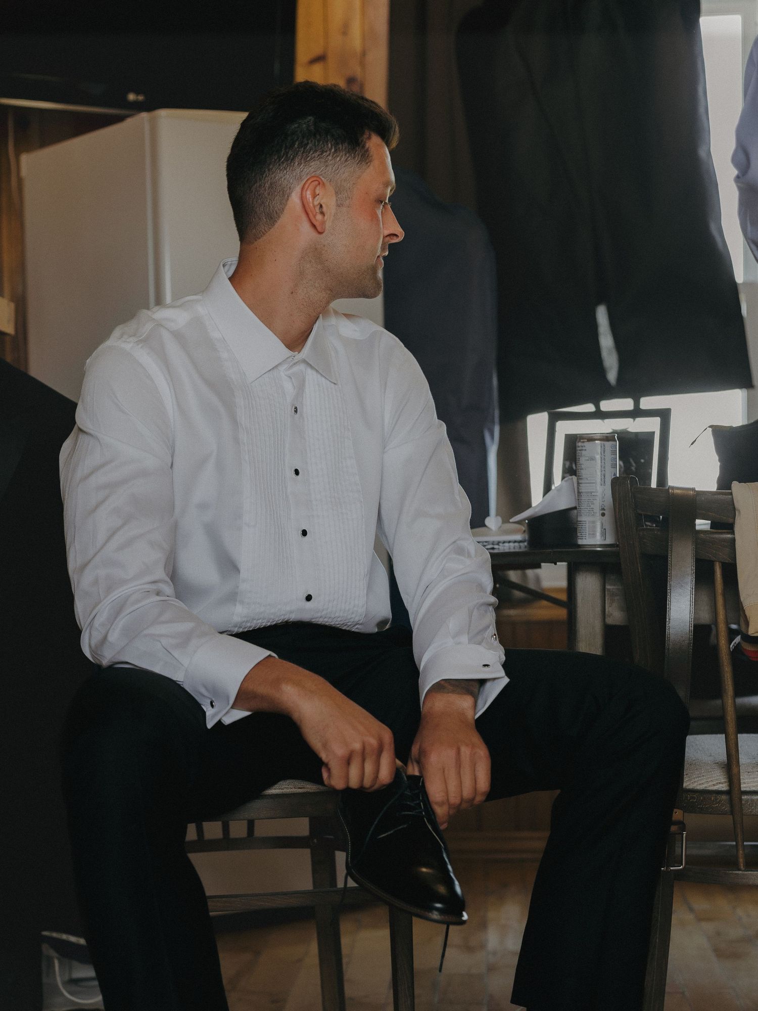 Groom gets ready for his wedding by putting on his shoes, and taking a moment to look at a photo of his late mother.