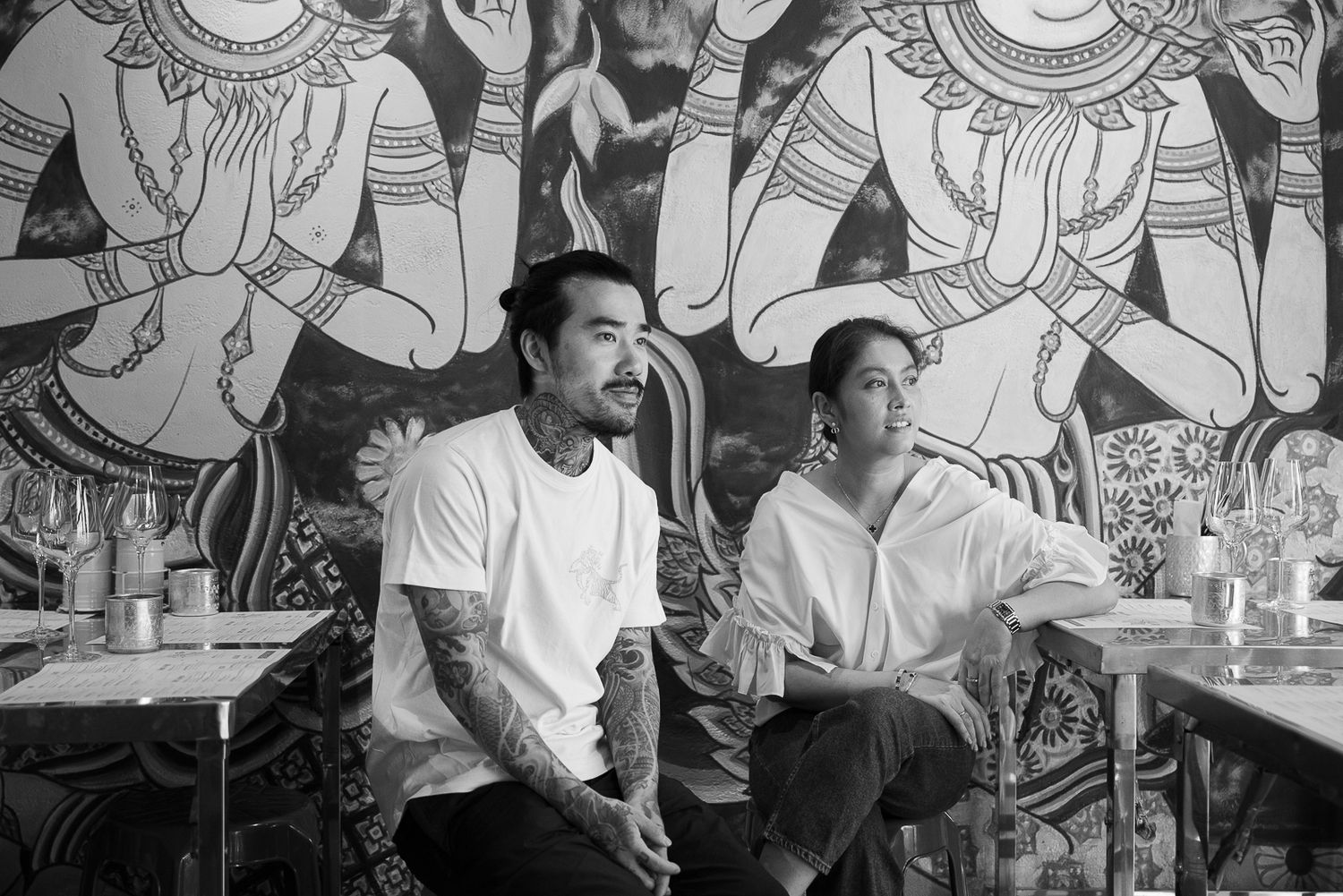 Chefs working in a busy restaurant kitchen with colorful mural artwork on the wall behind them.