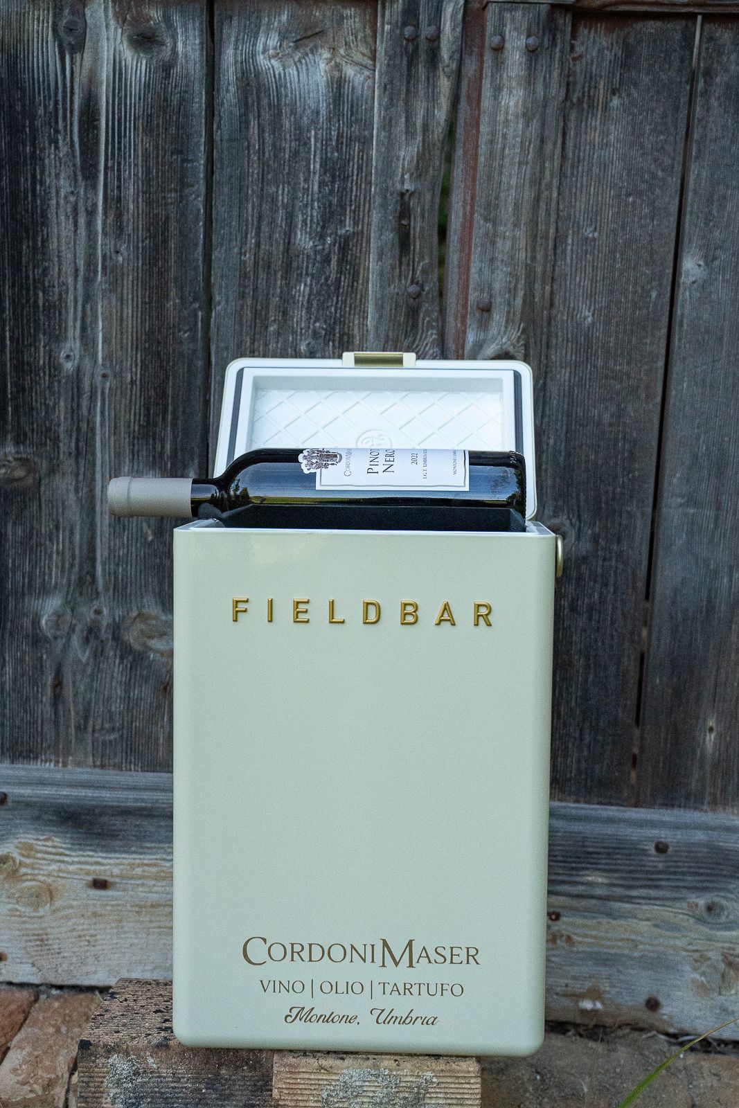 Vintage-style Fieldbar wine cooler containing CordoniMaser vino olio tartufo against rustic wooden backdrop.