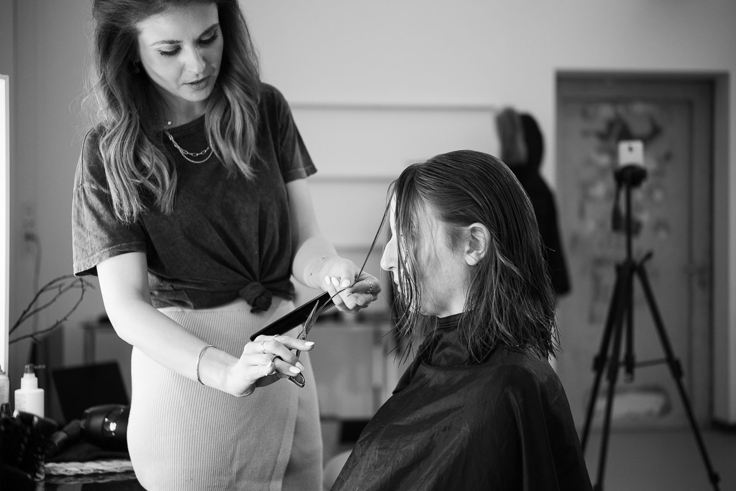 A professional makeup artist applies cosmetics to a client in a black and white photo series.