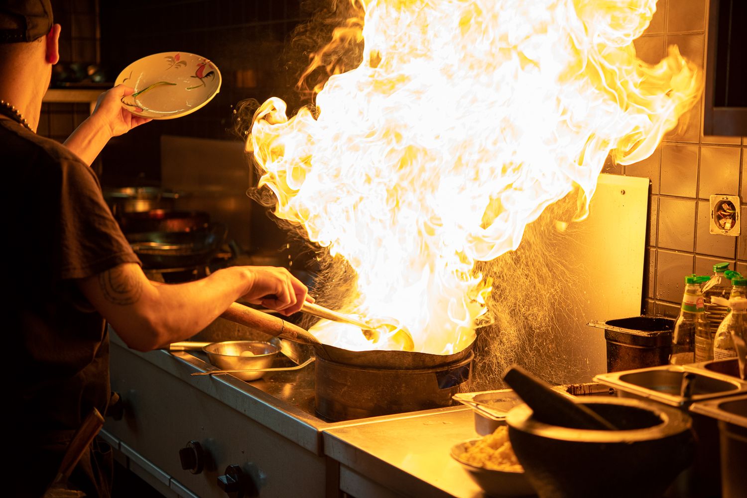 Dramatic shot of flames erupting from pan while cooking in professional kitchen.
