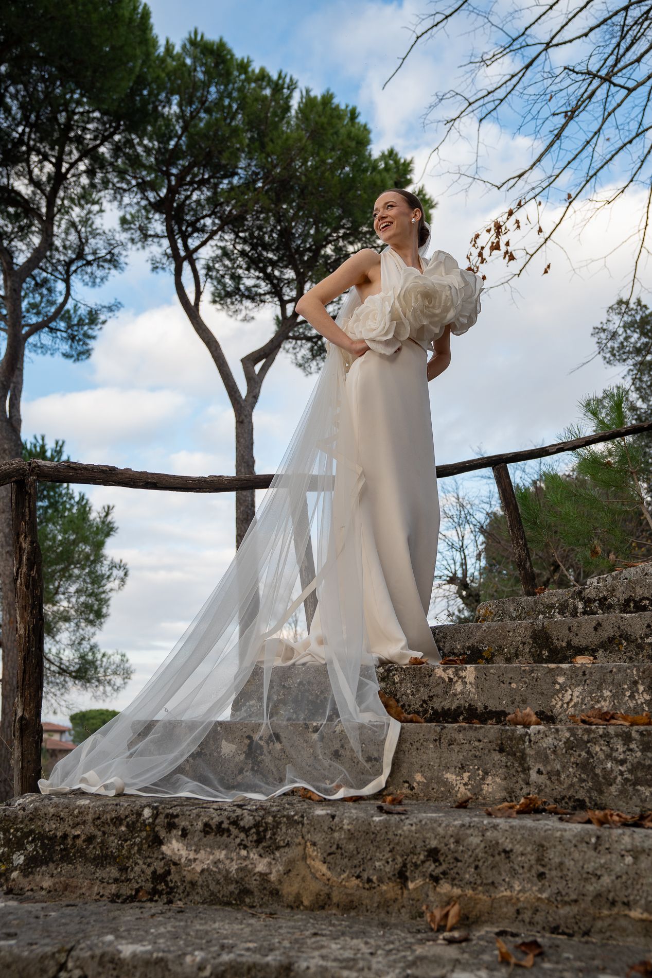 A sequence of photos showing a person in a flowing white dress moving gracefully along a stone wall in a garden setting.