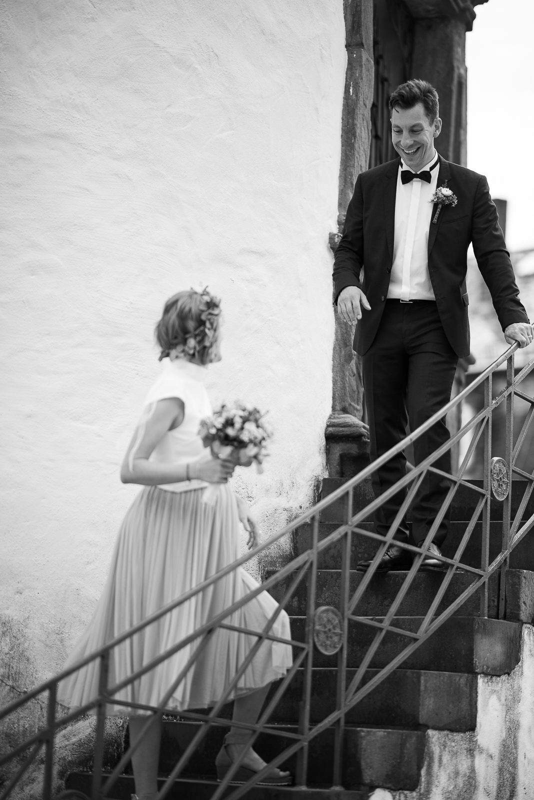 A sequence of black and white photos showing a couple in wedding attire descending outdoor stairs.