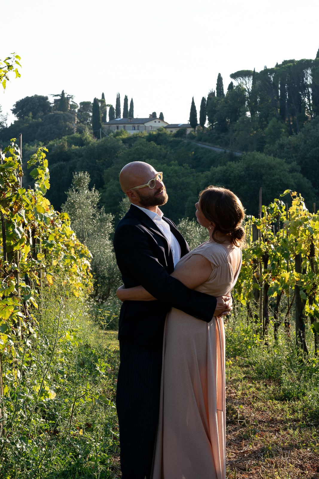 A romantic moment in an Umbrian vineyard with cypress trees and a villa in the background.