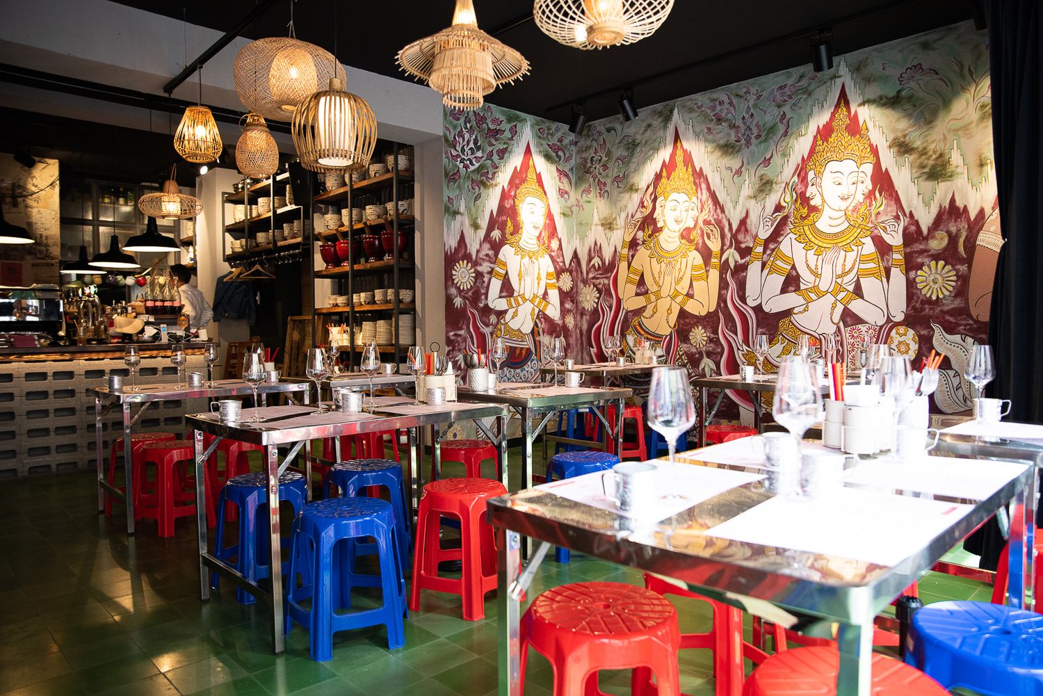 Asian restaurant interior with colorful plastic stools and decorative wall murals.