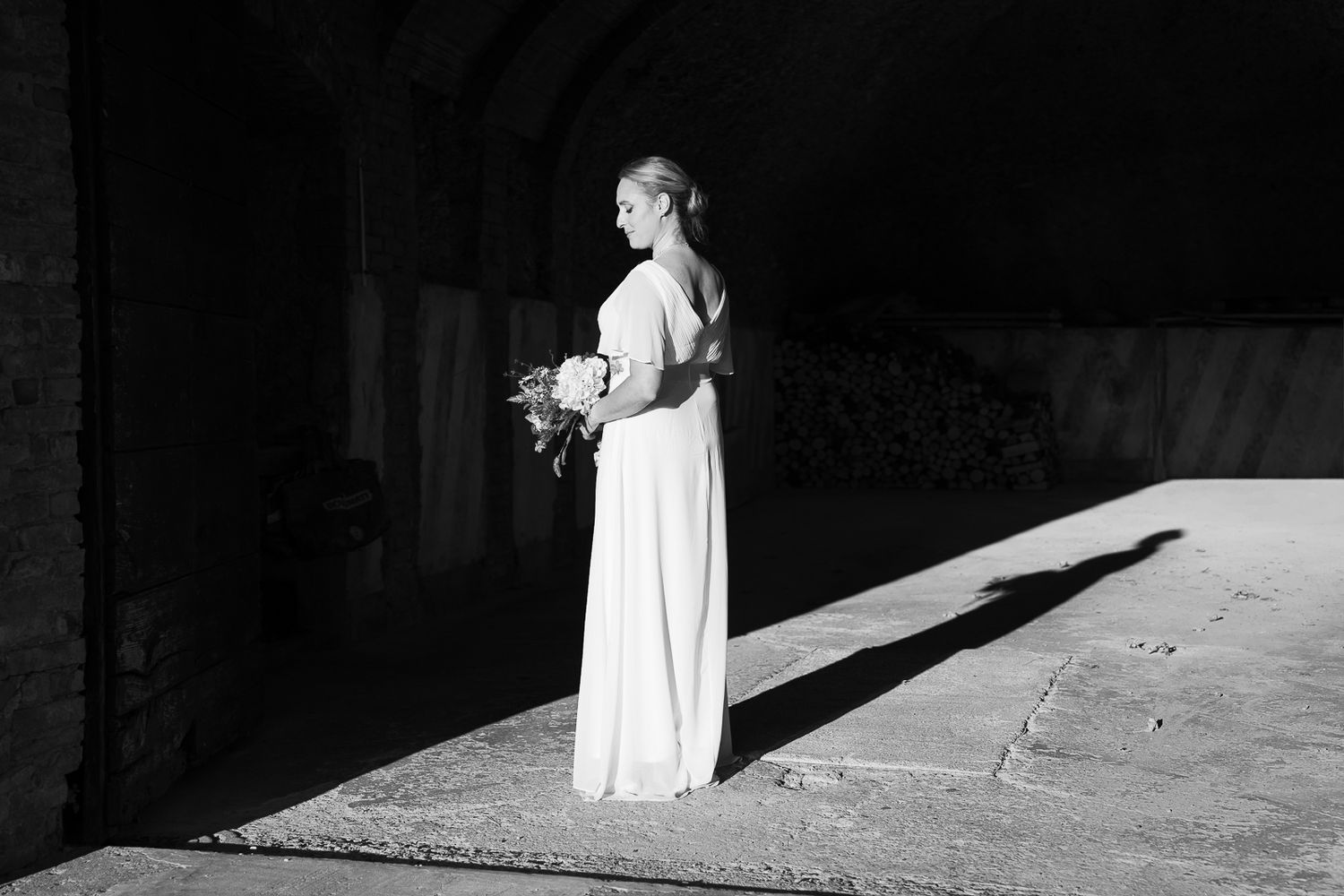 A dramatic black and white photo series shows a figure in white moving through shadows and light against stone walls.