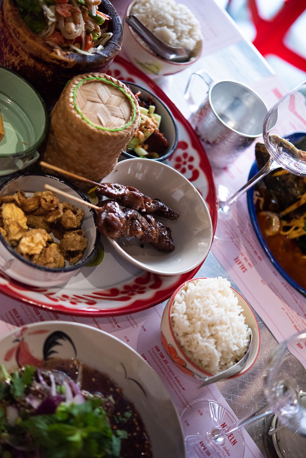 Overhead view of various Asian dishes and rice served in bowls on table.