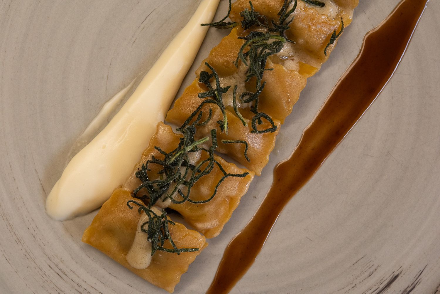Elegant white asparagus dish with herbs and sauce on curved ceramic plate.