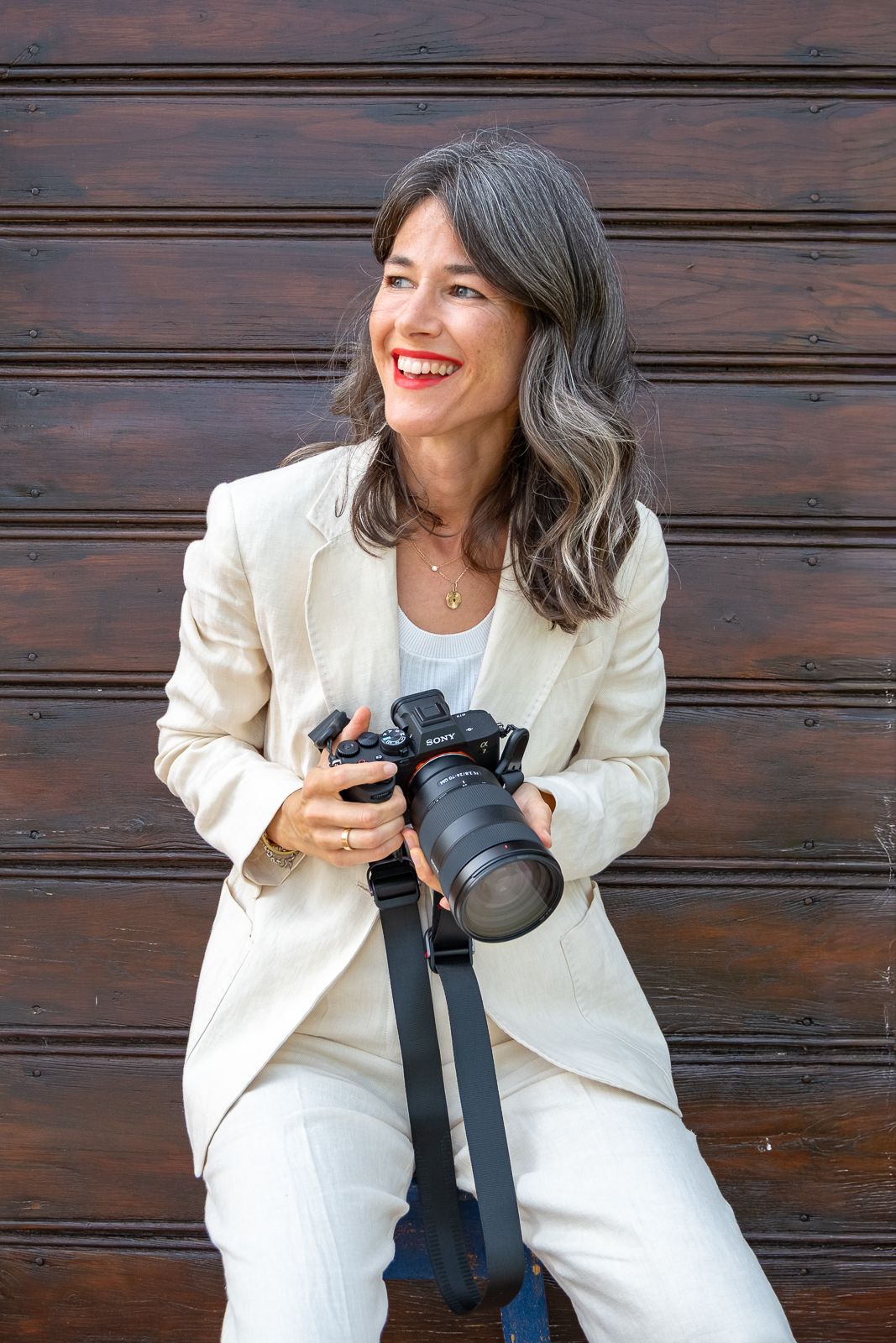A photographer in a white suit sits on wooden steps with a camera, showing a series of playful poses.