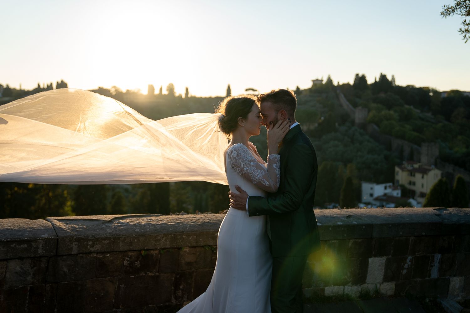 A romantic sunset silhouette of a couple embracing on their wedding day at a scenic outdoor venue.