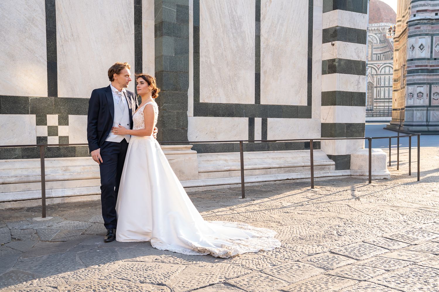 A romantic wedding couple shares tender moments in front of an ornate Italian church in Florence.
