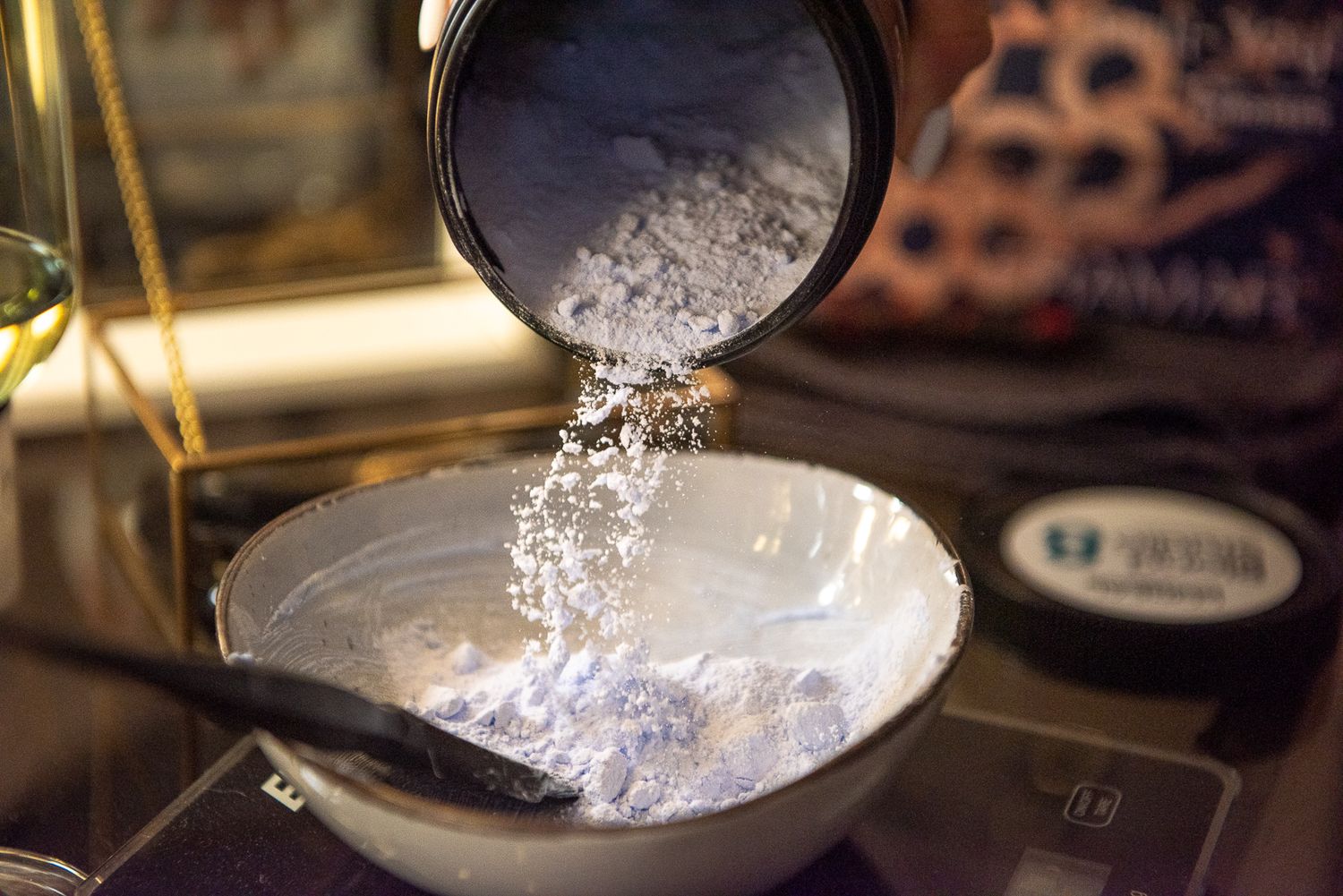 White powder being sifted through a fine mesh strainer.