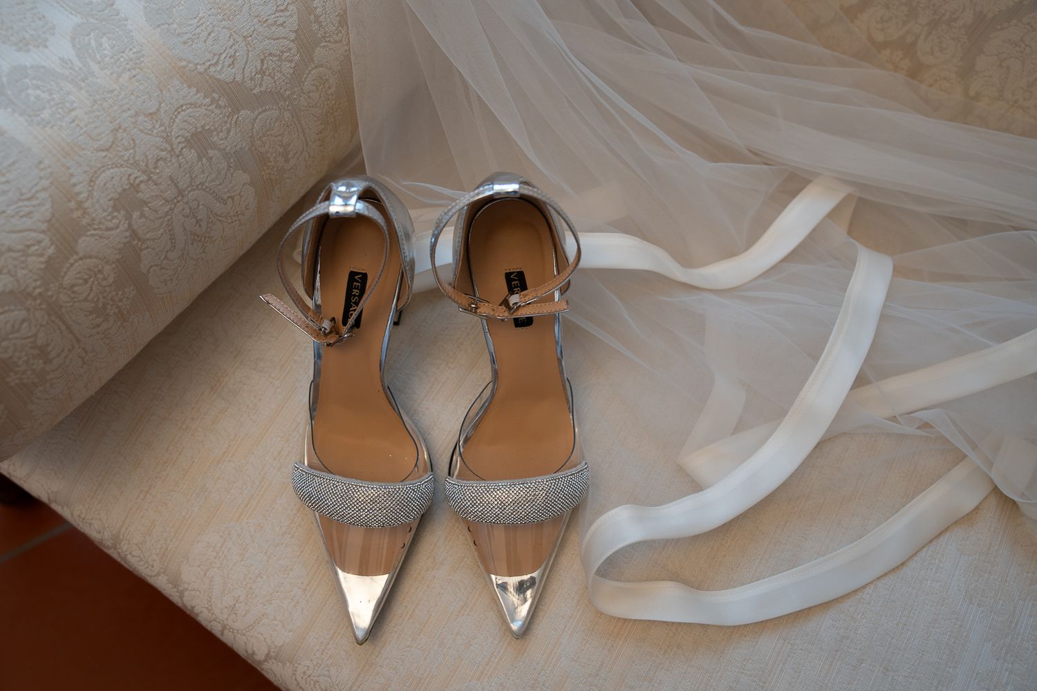 A series of elegant wedding shoes and accessories arranged in a row on white fabric.