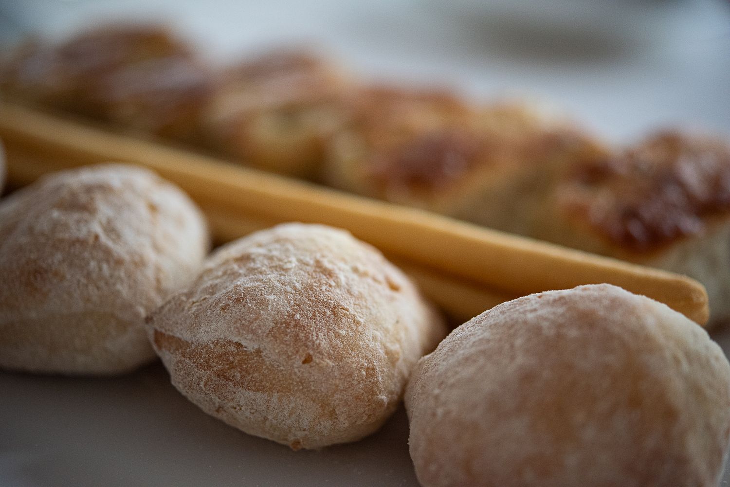 Fresh baked bread rolls cooling on a wooden surface.