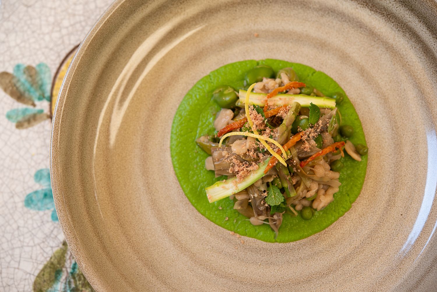 Modern plated dish featuring ingredients arranged on textured ceramic plate with green sauce.