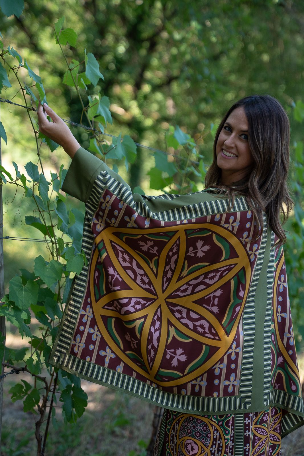 Colorful patterned fabric with floral mandala design displayed in natural outdoor garden setting.