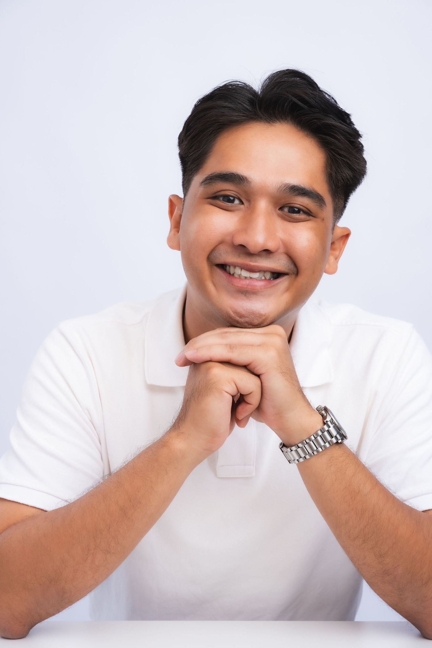 A series of four close-up portraits showing someone in a white polo shirt resting their chin on their hands against a light background.