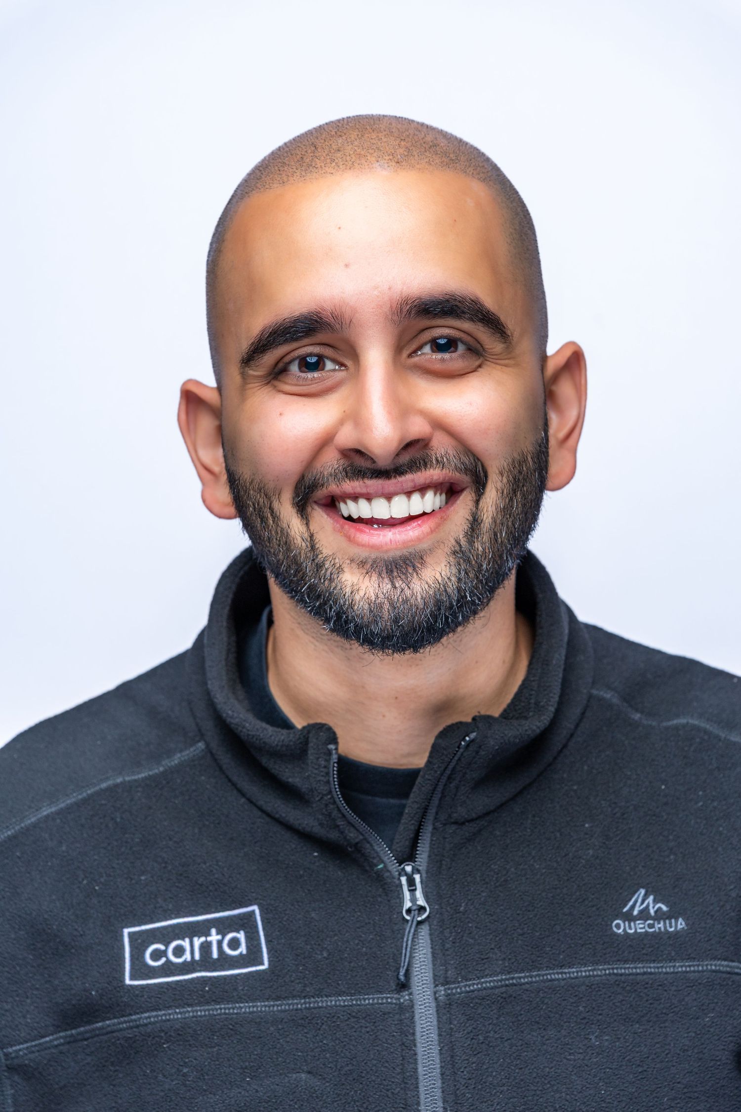 Professional headshot of someone wearing a black zip-up jacket with a Carta logo smiling at the camera.