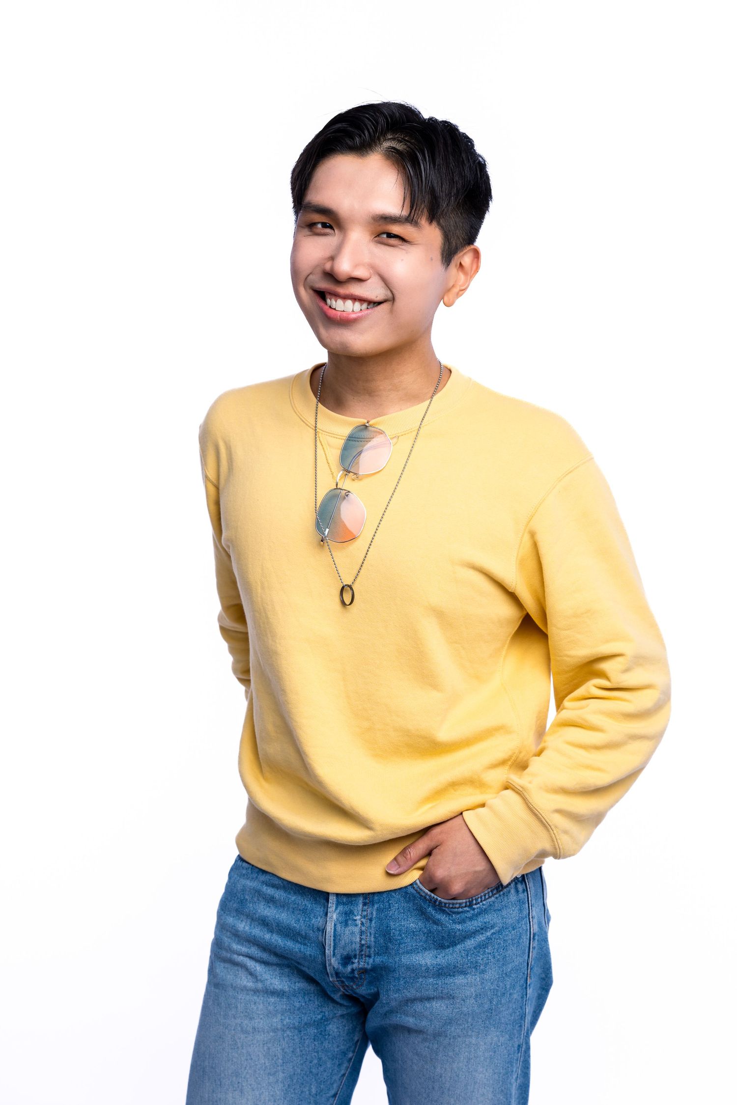Smiling person in a yellow sweater and blue jeans poses in three casual stances against a white background.