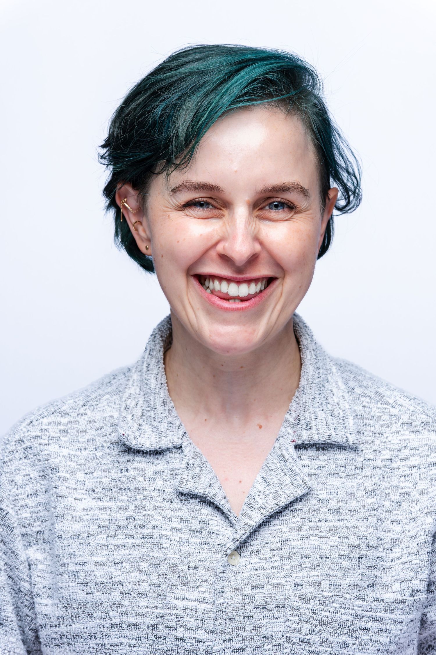 A sequence of four photos showing someone with teal-colored hair smiling progressively wider in a gray sweater.