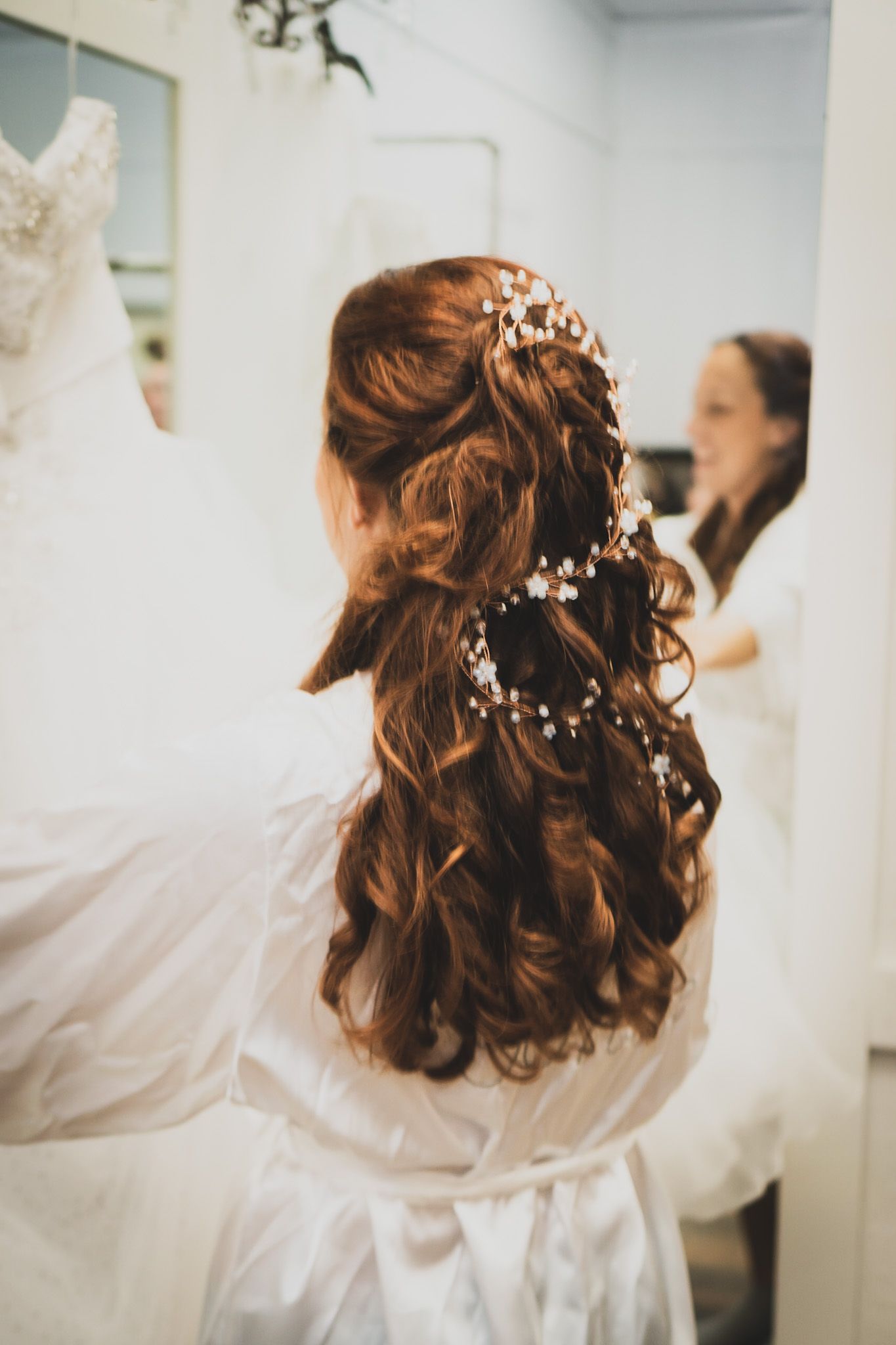 Elegant bridal hairstyle featuring pearl accents and soft curls shown from behind.