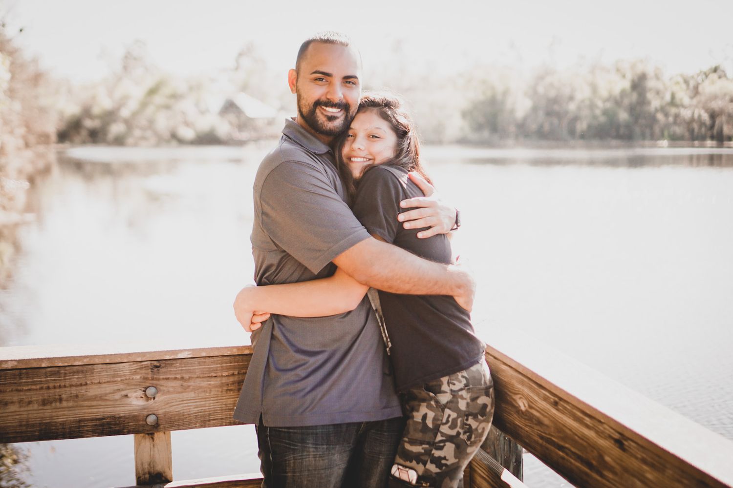 Happy couple sharing intimate outdoor moments on a wooden deck during an engagement photoshoot.