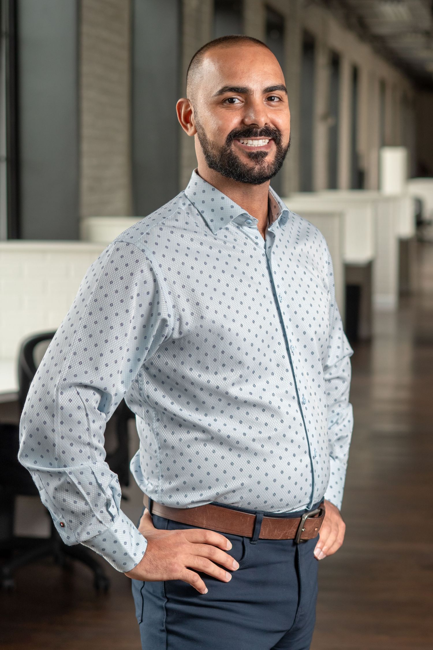 Professional wearing a polka dot dress shirt and navy slacks poses in a series of dynamic poses in an office hallway.